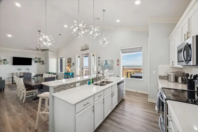 a large white kitchen with stainless steel appliances kitchen island a large counter top a sink and a chandelier