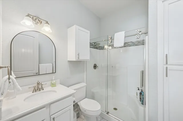 a bathroom with a toilet sink vanity granite and shower