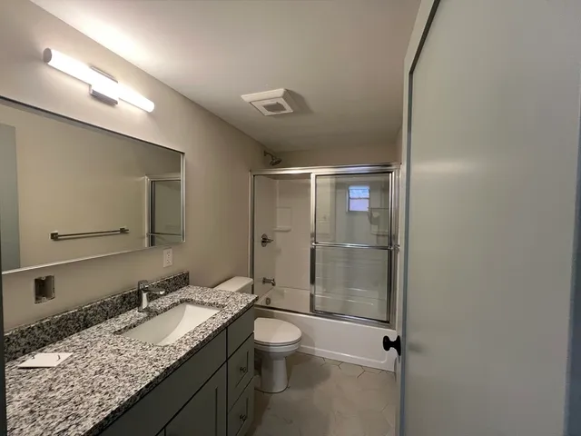 a bathroom with a granite countertop sink toilet and shower