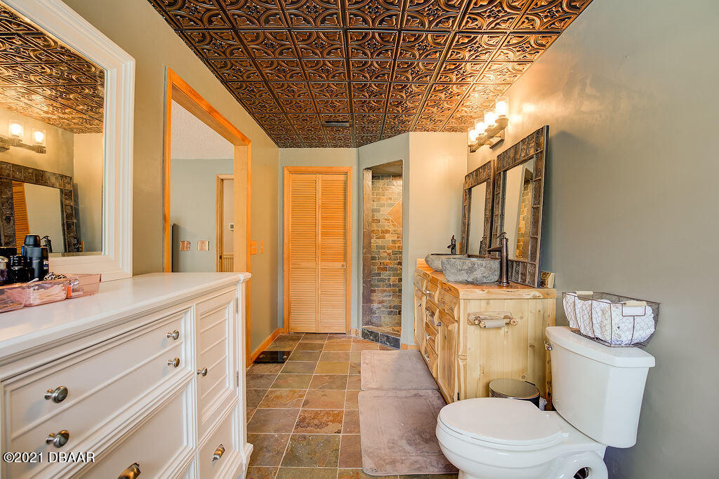 114 Pine Creek Court Ormond Beach, FL 32174 - Photo 25 of 41 a bathroom with a granite countertop sink a toilet a mirror and shower