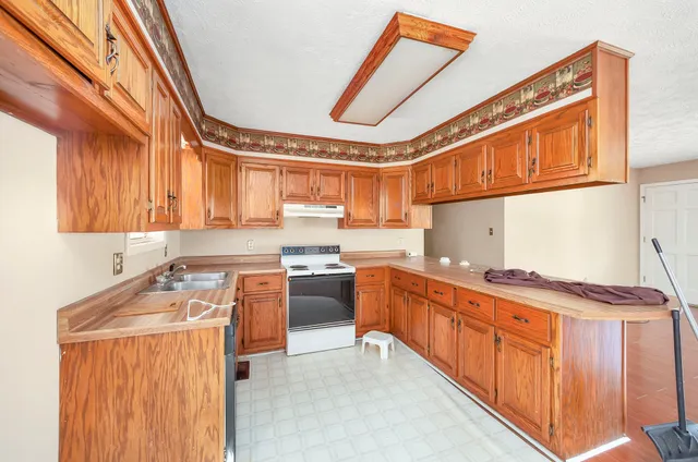 a kitchen with stainless steel appliances granite countertop a stove a sink and a refrigerator
