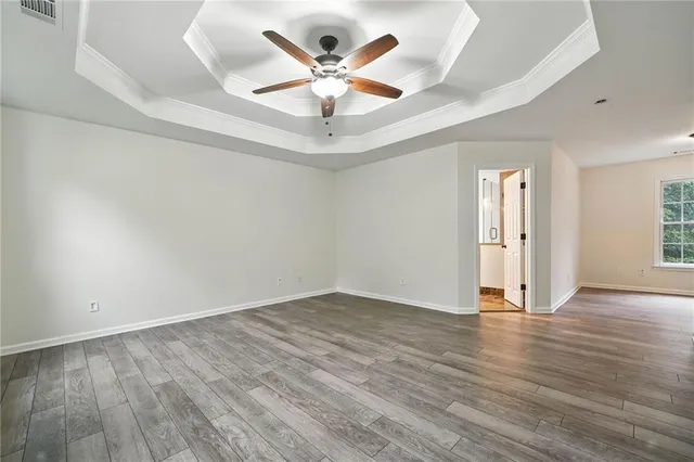 an empty room with wooden floor fan and windows