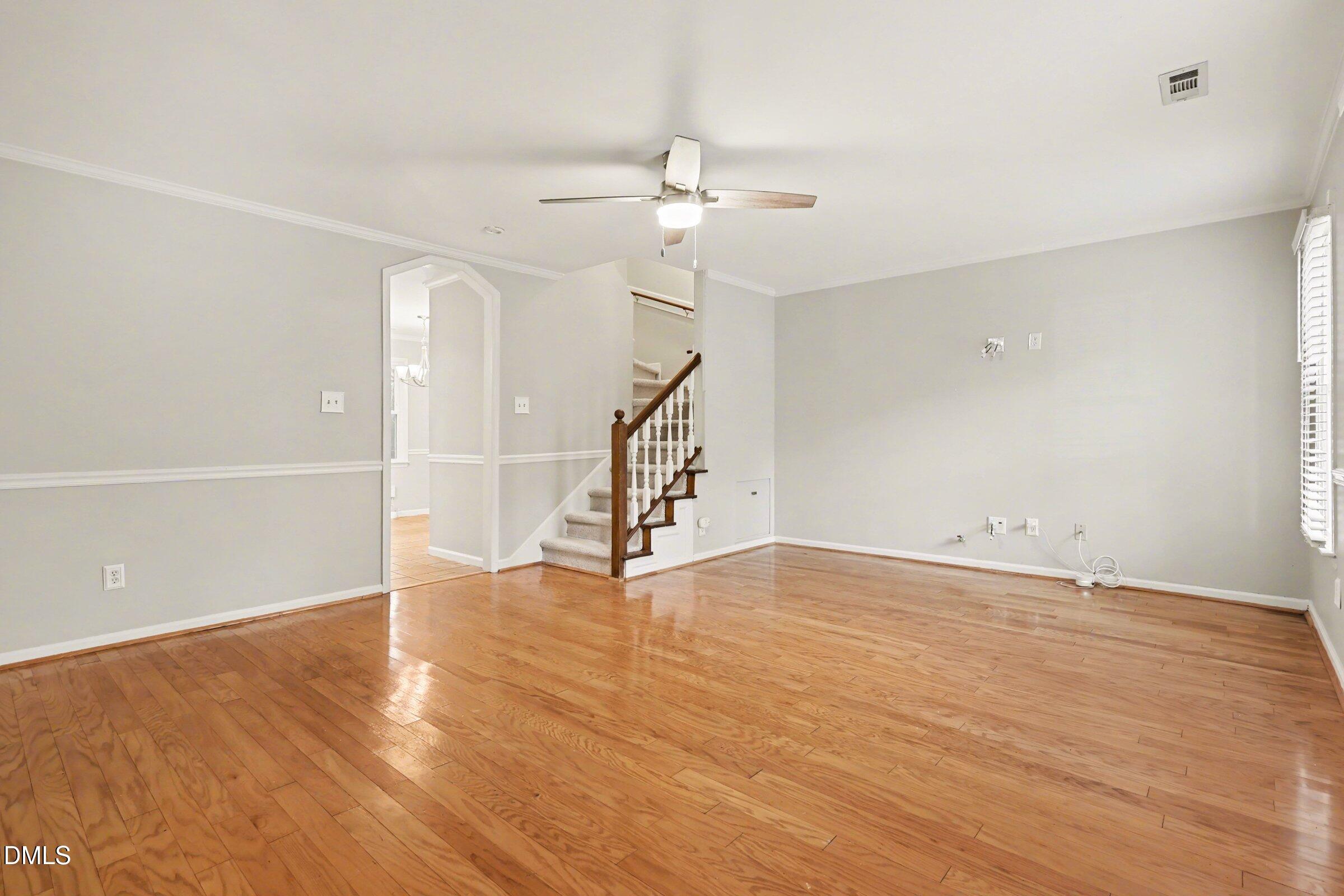5645 Hamstead Crossing Raleigh, NC 27612 - Photo 8 of 35 a view of an empty room with wooden floor and a ceiling fan