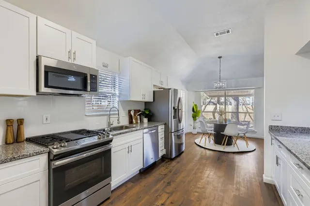 a kitchen with stainless steel appliances granite countertop a stove a sink dishwasher a refrigerator a microwave oven with cabinets and wooden floor