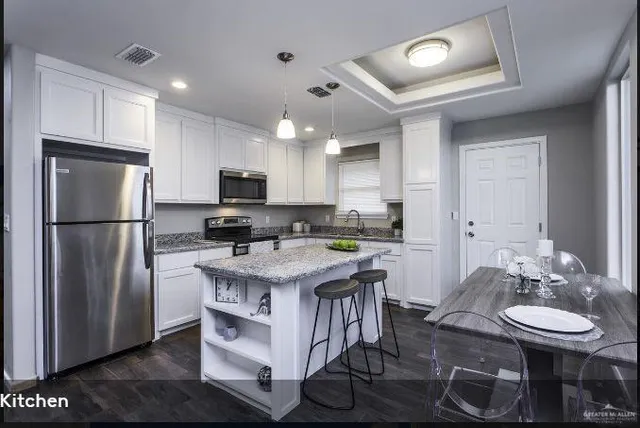 a kitchen with stainless steel appliances granite countertop a stove a refrigerator a sink dishwasher a dining table and chairs with wooden floor