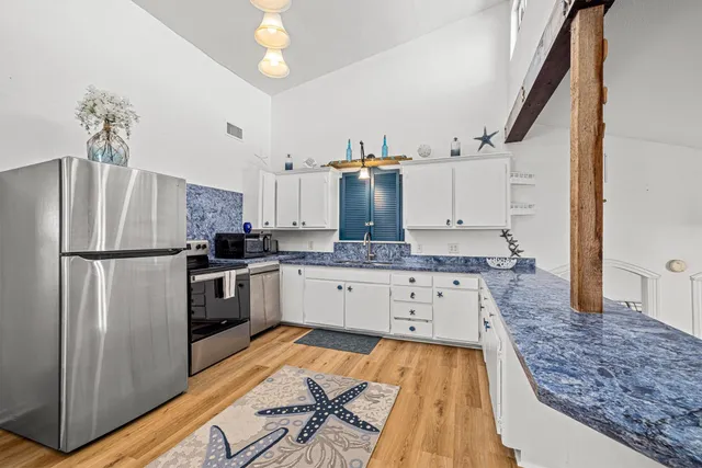 a kitchen with stainless steel appliances granite countertop a refrigerator sink and white cabinets