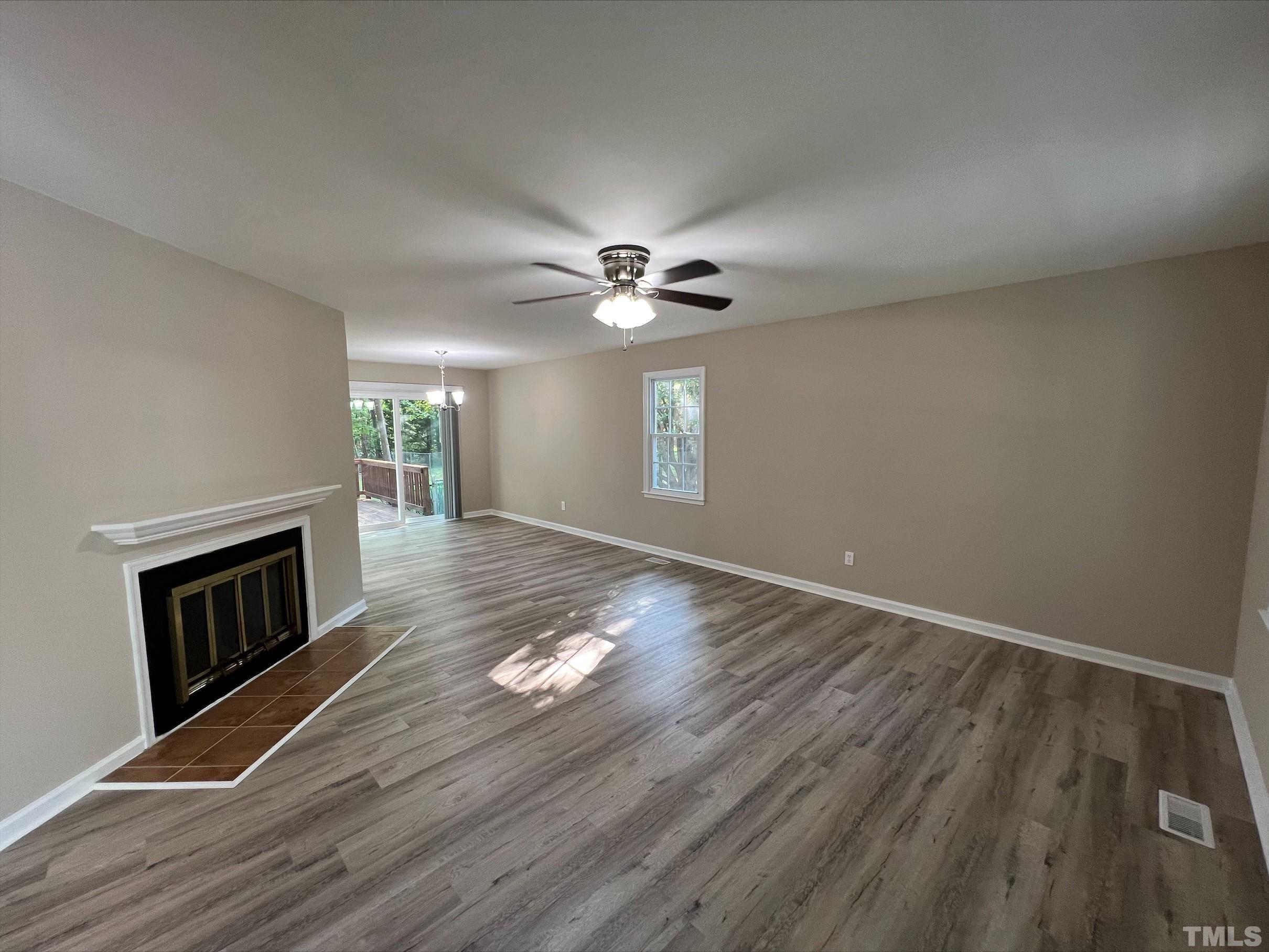 605 Sawmill Road Raleigh, NC 27615 - Photo 6 of 26 an empty room with wooden floor fireplace and windows
