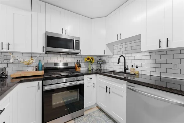 a kitchen with cabinets stainless steel appliances a sink and a microwave