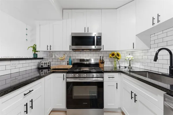 a kitchen with stainless steel appliances a stove sink and white cabinets