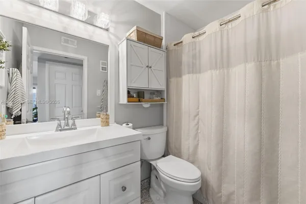 a bathroom with a sink a toilet and shower curtain