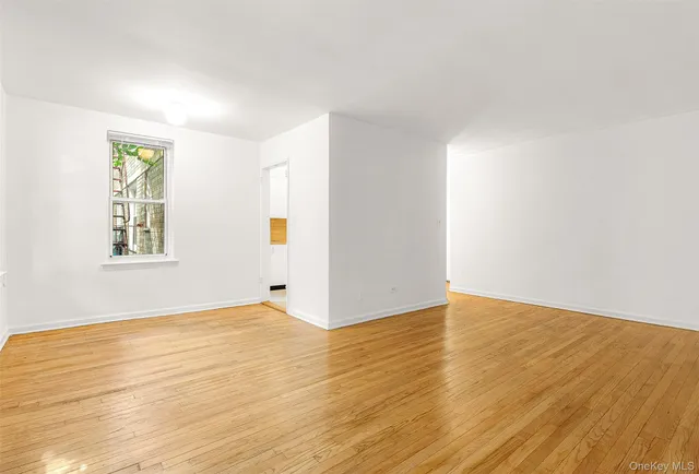 a view of an empty room with wooden floor and a window
