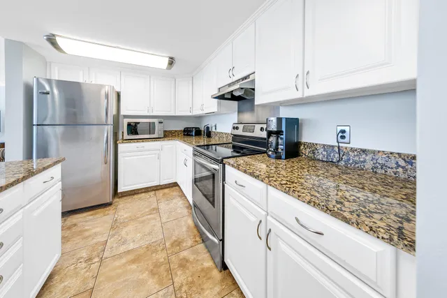 a kitchen with stainless steel appliances granite countertop a stove a refrigerator and a white cabinets
