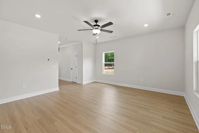 an empty room with wooden floor window and ceiling fan