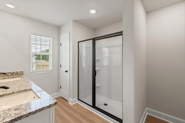 a bathroom with a granite countertop sink a mirror and shower