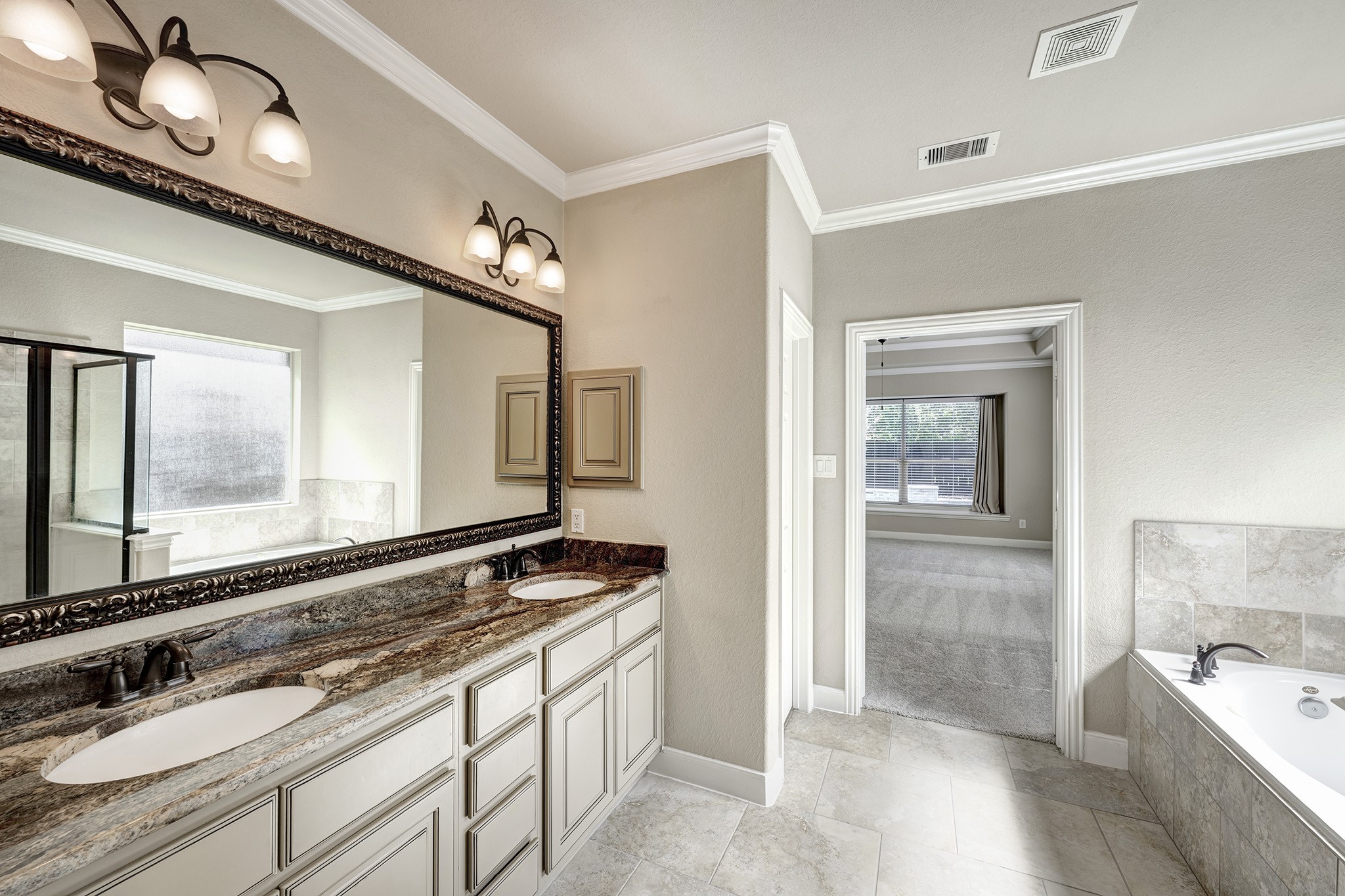 11 Red Wagon Drive Spring, TX 77389 - Photo 15 of 32 The serene primary bath has a gorgeous stone countertop with framed mirror, soaking tub, and glass enclosed shower.