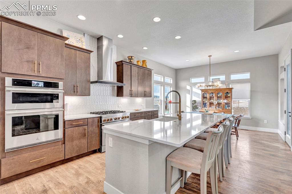 2402 Parma Court Colorado Springs, CO 80921 - Photo 12 of 45 a kitchen with stainless steel appliances granite countertop a stove top oven a sink dishwasher a dining table and chairs with wooden floor