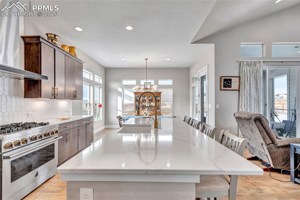 2402 Parma Court Colorado Springs, CO 80921 - Photo 13 of 45 a view of a kitchen with kitchen island a stove a sink wooden floor and living room view
