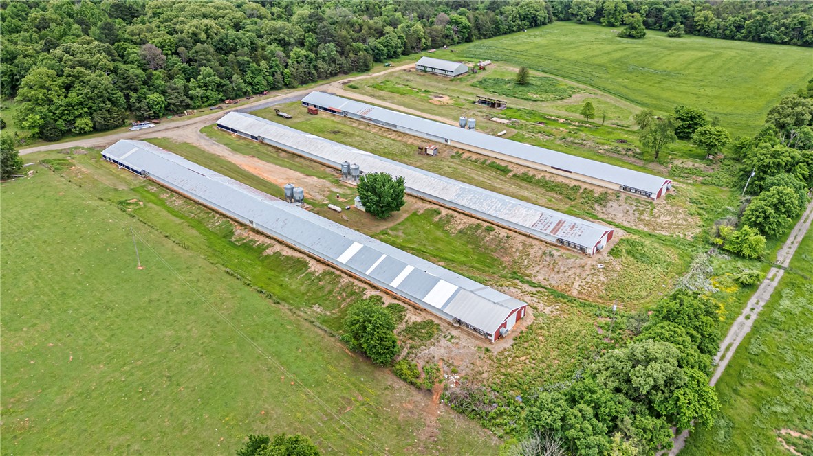 Expansive rural property featuring four long agricultural structures with metal roofs
