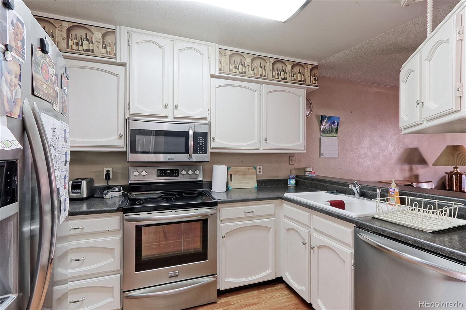 12133 Bannock Circle, Unit B Westminster, CO 80234 - Photo 3 of 14 a kitchen with stainless steel appliances granite countertop a sink a stove a microwave and cabinets