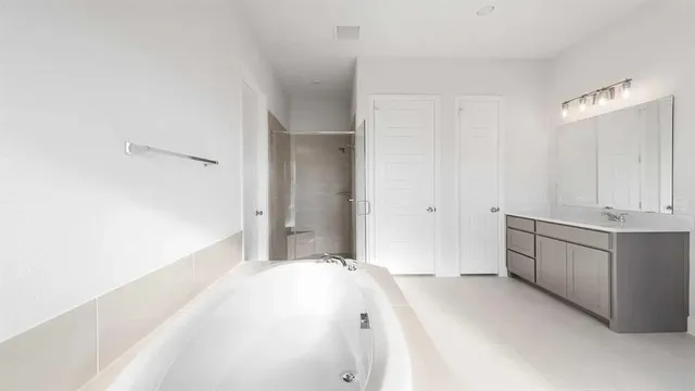 a spacious bathroom with a tub sink and mirror