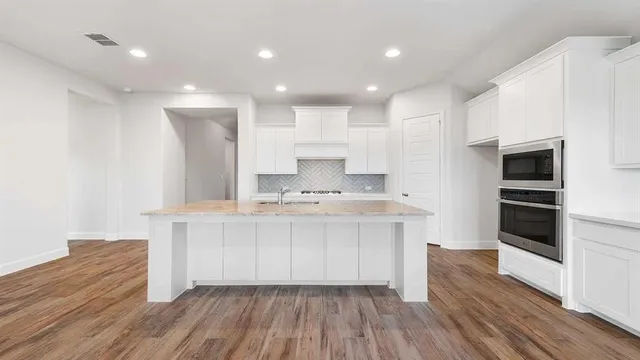 a kitchen with stainless steel appliances a sink and wooden floor