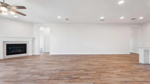 a view of an empty room with wooden floor fireplace and a window