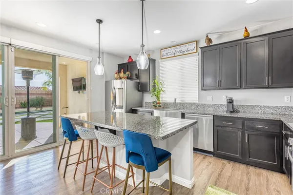 a kitchen with stainless steel appliances granite countertop a table chairs sink and cabinets