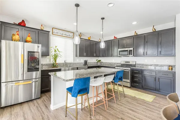 a kitchen with stainless steel appliances granite countertop a sink a stove a refrigerator and island with wooden floor