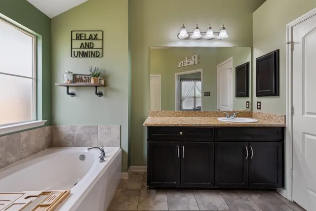 a bathroom with a tub sink and mirror