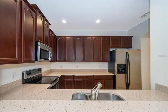 a kitchen with stainless steel appliances wooden cabinets a refrigerator and a sink