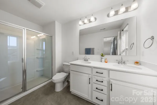 a spacious bathroom with a double vanity sink toilet mirror and shower