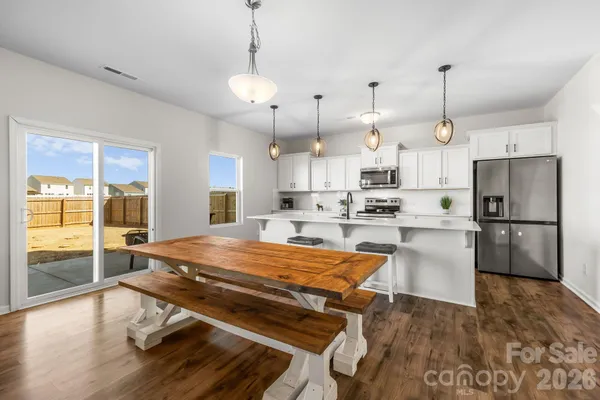 a kitchen with stainless steel appliances kitchen island granite countertop a refrigerator a stove and white cabinets with wooden floor