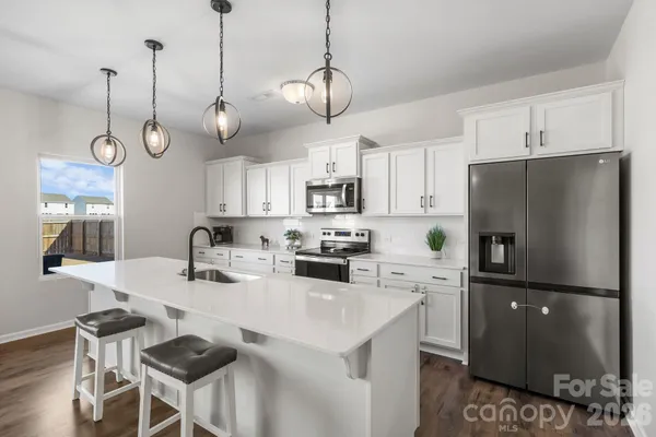 a kitchen with stainless steel appliances granite countertop a sink a stove a refrigerator a center island a refrigerator and a chandelier