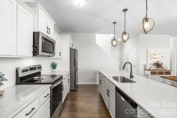 a kitchen with stainless steel appliances granite countertop a sink a stove and a wooden floors