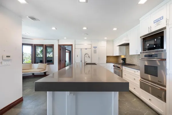 a large kitchen with kitchen island a large counter top stainless steel appliances and cabinets
