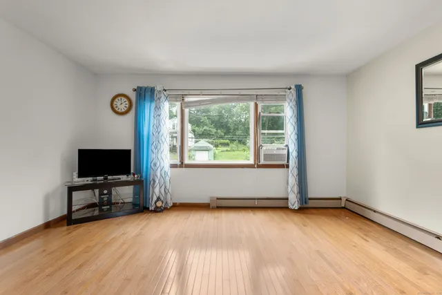 a view of an empty room with a window and wooden floor