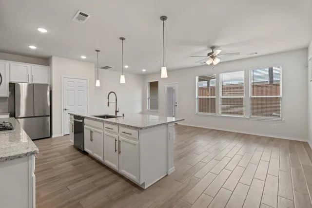 a large kitchen with granite countertop a large counter top appliances and cabinets