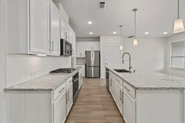 a kitchen with stainless steel appliances granite countertop a sink stove and refrigerator