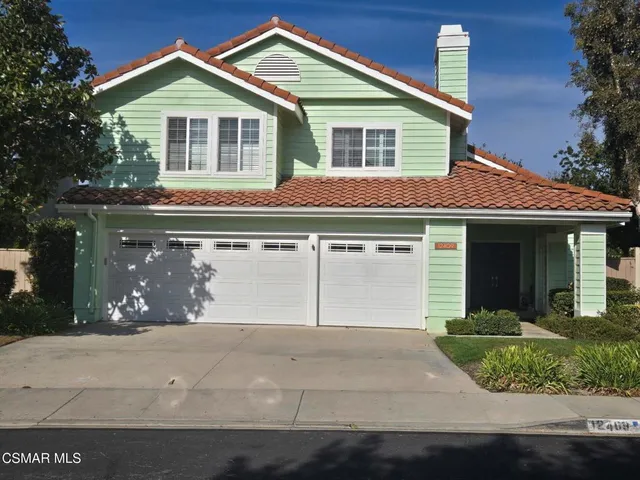 a front view of a house with garage and plants