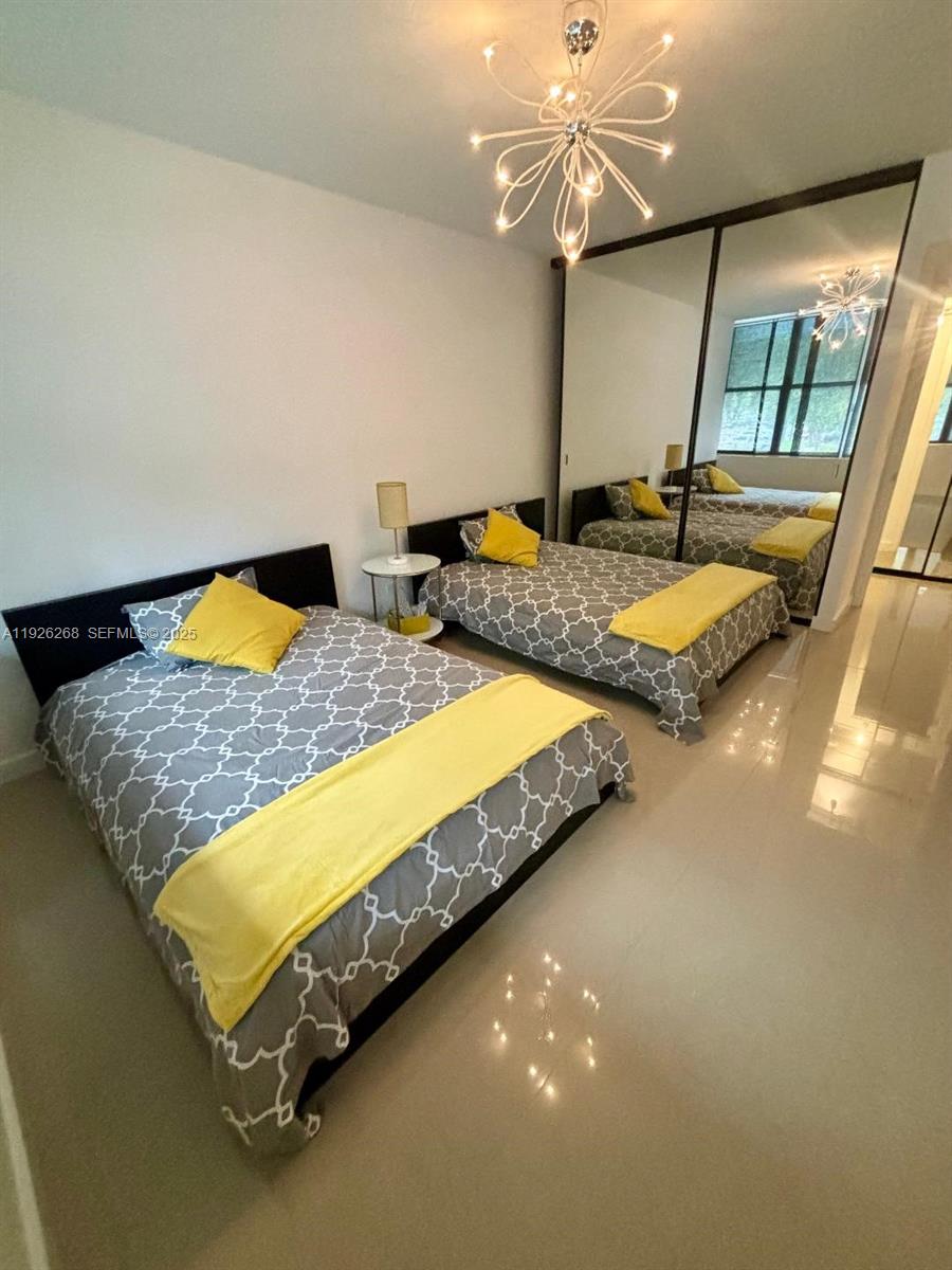 7441 Wayne Avenue, Unit 1R Miami Beach, FL 33141 - Photo 13 of 25 a bedroom with a bed and a chandelier