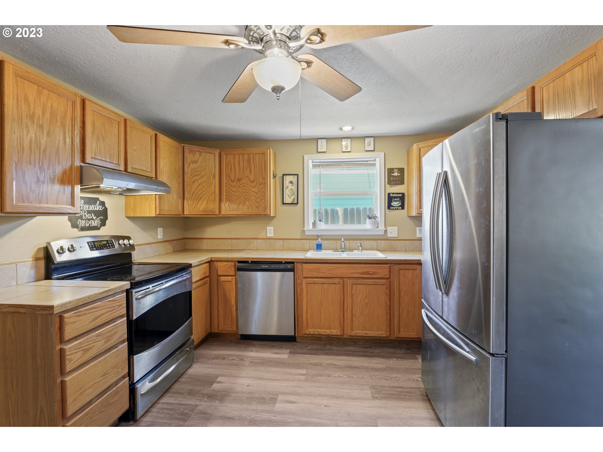 760 28th Street Springfield, OR 97477 - Photo 11 of 30 a kitchen with stainless steel appliances granite countertop a refrigerator a sink dishwasher a stove a dining table and chairs with wooden floor