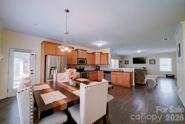 a living room with furniture kitchen view and a wooden floor