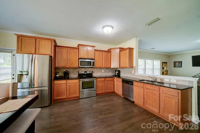 a kitchen with stainless steel appliances granite countertop a stove top oven a sink dishwasher a refrigerator and cabinets with wooden floor