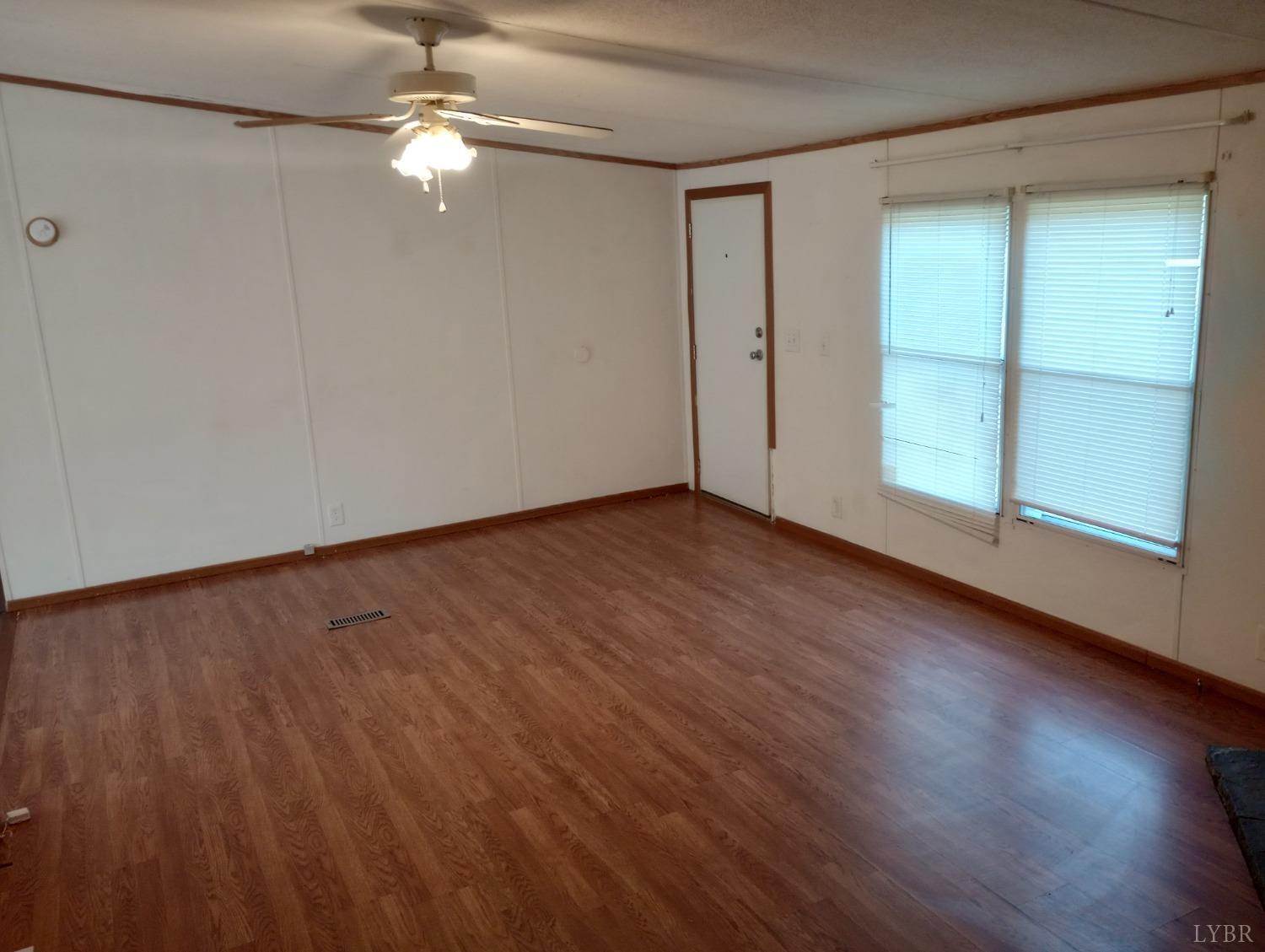 581 Red Oak School Road Rustburg, VA 24588 - Photo 3 of 17 an empty room with wooden floor fan and windows