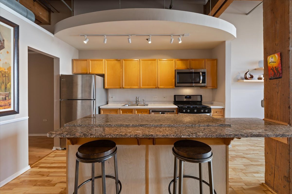 1632 South Indiana Avenue, Unit 403 Chicago, IL 60616 - Photo 4 of 23 a kitchen with granite countertop kitchen island stainless steel appliances a refrigerator and a stove top oven
