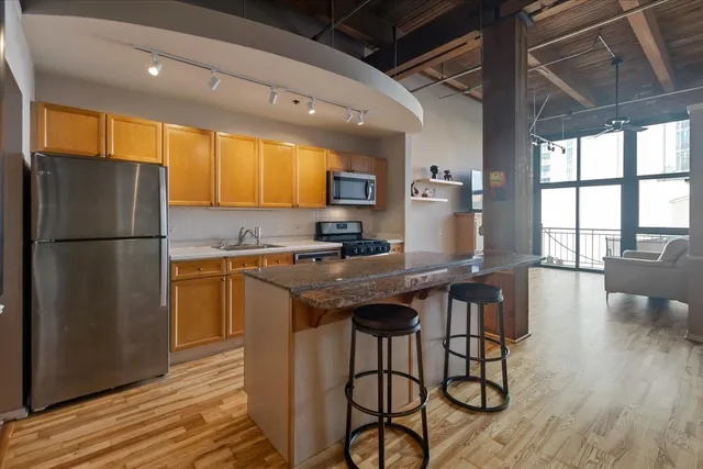 a kitchen with stainless steel appliances granite countertop a refrigerator a sink dishwasher a stove and a refrigerator with wooden floor