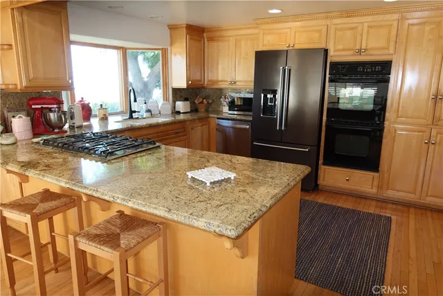 a kitchen with stainless steel appliances granite countertop a sink a refrigerator and a granite counter tops