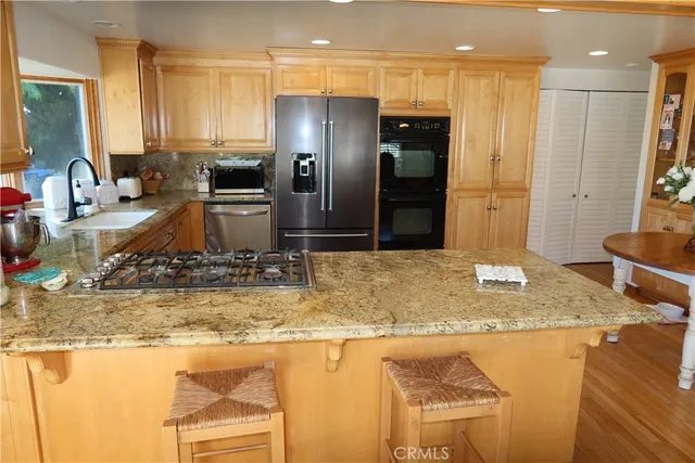 a kitchen with stainless steel appliances granite countertop a sink a stove and a refrigerator