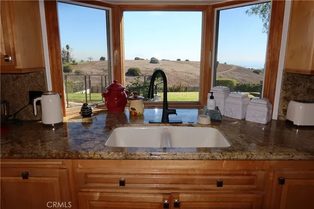 a kitchen with a granite countertop sink and a large window
