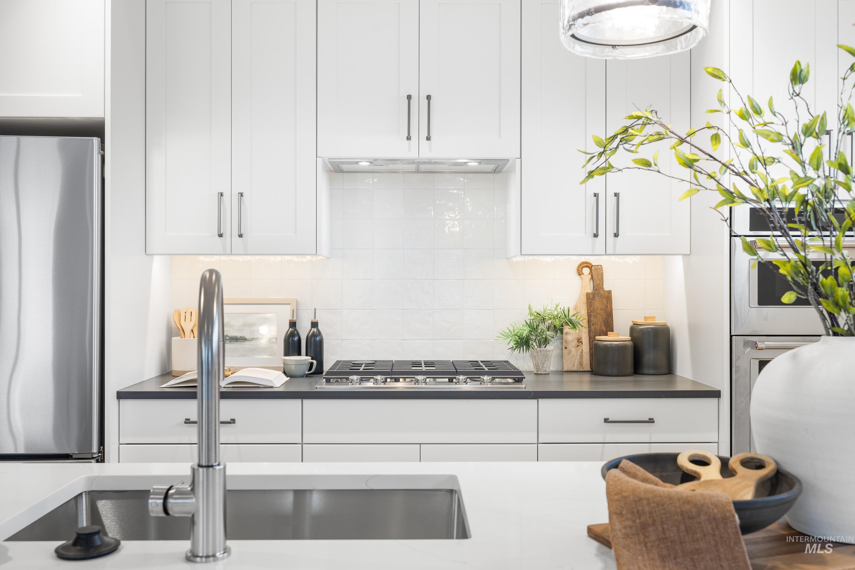 3071 North Lapis Avenue Meridian, ID 83646 - Photo 14 of 50 Kitchen with stainless steel appliances, white cabinetry, and decorative backsplash